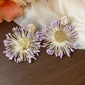 Detailed view of handmade raffia flower stud earrings with hammered gold centers - Gold-Purple