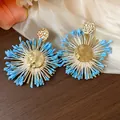 Macro view of the blue raffia petals and hammered golden core of these earrings. - Gold-Blue
