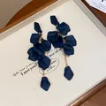 Elegante vista macro di orecchini a petalo blu navy con sottili nappe a catena dorata - Blu scuro