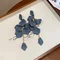 Primo piano di orecchini a nappa con petali blu opachi ed eleganti catene d'oro - Grigio