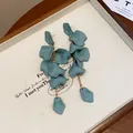 Primo piano di orecchini a nappa con petali blu opaco e catene dorate. - Azzurro