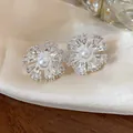 Macro view of flower-shaped earrings with central pearl and clear cubic zirconia stones - Silver Ear Clip Style (Pair)