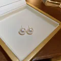 Primer plano de elegantes pendientes de perlas redondas en un joyero con borde dorado. - 6# Pendiente de Perla Minimalista / 10mm / Blanco
