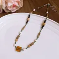 Handmade bohemian beaded necklace with an amber glass pendant displayed on white plate - Style 81# Necklace / Silver-Brown-Green