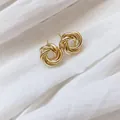 Elegante goldene Ohrstecker mit verschlungenem Knoten auf weißem Leinenhintergrund - Gedrehte Spiral-Ohrstecker (2) / Gold