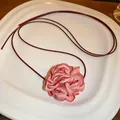 Detail of a pink fabric flower choker with a burgundy cord on a white plate - Pink Style 2