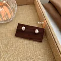 Elegant 8mm white pearl stud earrings presented on a minimalist dark wood display card - 8mm / White