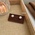 Elegant 10mm high-gloss pearl stud earrings with silver needles on a wooden stand - 10mm / White