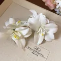 Détail rapproché des pinces à cheveux en lys blanc avec des étamines jaunes réalistes - Pinces à cheveux bec de canard / 1 Pièce / Blanc