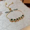 Nahaufnahme eines goldenen Armbands im französischen Stil mit grünen Zirkonia-Steinen. - Regulär (21# Armband) / Gold-Grün