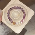 Detail of a gemstone beaded bracelet with purple and yellow crystals on a wooden tray. - Style 30 / Purple