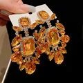 Close-up of orange square and teardrop rhinestone vintage statement earrings - Gold
