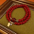 Close-up of a double-strand red beaded bracelet with a gold Fu charm and purple heart. - Style 52 (Fu Character Tag) / Gold-Red