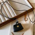 Detailed view of a mini black leather bag pendant on a trendy black cord necklace - Black