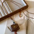 Close-up of a vintage brown leather bag pendant on a stylish long cord sweater necklace. - Brown