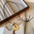 Close-up of geometric golden pendant on a minimalist leather cord necklace - Coffee-Gold