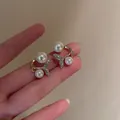 Detail view of pearl fishtail earrings with sparkling rhinestones on golden metal - Pearl Fish Tail Stud Earrings / Gold