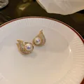 Close-up of elegant gold fish-tail earrings with pavé crystals and pearl. - Large Pearl Fishtail Studs / Gold