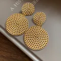 Close-up of elegant gold-toned hollow mesh circular drop earrings on a gray background - Hollowed-out Round Pendant / Gold