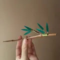 Close-up detail of a traditional Chinese-style bamboo hair stick with translucent green leaves - Brown And Green