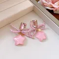 Detailed view of pink pearl bow earrings with glittery resin star pendants - Earrings / Pink