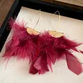 Close-up of wine red feather tassel earrings with textured gold metal accents - Hook Style (HE29174) / Alloy Ear Hook / Red