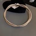 Close-up of a multi-layered silver snake chain necklace on a heart-shaped tray. - Wrapped Necklace / Silver