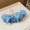 Exquisite Nahaufnahme von blauen Stoffblumen auf einem stilvollen goldenen Haarschmuck - Haarstab / Blau