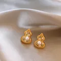 Elegante goldene Kürbis-Ohrringe mit Perlen und Zirkonia auf Satin-Hintergrund - Hohle Kürbis-Textur (HE29329) / Gold