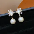 Elegant four-pointed star earrings with central white stone and dangling pearls detail - Starburst Pearl Style / Gold
