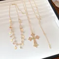 Detail view of gold-tone necklaces with rhinestone cross and star tassel charms - Three-Piece Set / Gold