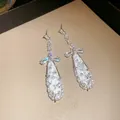 Close-up of elegant bowknot and oval drop earrings with sparkling cubic zirconia. - Oval Tassel Style / Silver