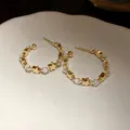 Dettaglio ravvicinato di orecchini a cerchio a C dorati con stelle e zirconi alternati. - Tops / Oro