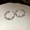 Primo piano dettagliato di orecchini a C argentati con zirconi e motivi a stella. - Tops / Argento