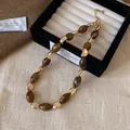 Makroansicht von braunen Tigerauge-Perlen und goldenen Metallakzenten auf Schmuck - 5# Halskette-Oval-Braun
