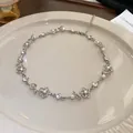 Elegante silberne Blumenkette mit Kunstperlen und Kristallen auf beigem Teller - 37# Halskette-Blume