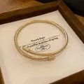 Detailed view of a golden twisted metal cable bangle presented in a luxury wooden jewelry box - Gold