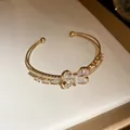 Detalle del brazalete abierto dorado de doble capa con motivo de mariposa en circonitas - Mariposa Blanco / Dorado