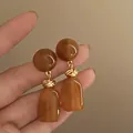 Macro detail of French vintage amber resin earrings with elegant golden knot accents. - Silver Earring Post - Coffee Round