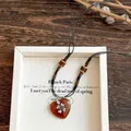 Close-up of the ethnic heart-shaped pendant and flower charm on a beaded cord necklace - 79# Necklace - Brown - Black