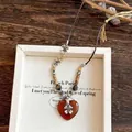 Detail view of a vintage beaded heart pendant necklace with ethnic flower accents. - 80# Heart Flower / Amber