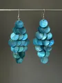 Gros plan détaillé montrant les couches irisées de boucles d'oreilles pendantes en nacre bleue - Crochets d'oreilles à pompons / Bleu Lac