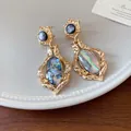 Macro view of vintage gold-tone earrings featuring shimmering oval abalone shell inlays - Silver Post Shell Oval Style / Gold With Iridescent Multicolor