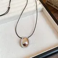 Close-up of a minimalist silver oval pendant on a black cord necklace in a display tray. - Silver Mirror Oval Style (16#) / Adjustable / Silver-Black