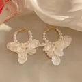 Eleganti orecchini a cerchio dorati con perle bianche e petali traslucidi. - Bianco Crema