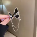 Élégante broche papillon argentée et noire avec strass étincelants et glands à chaînes fines - Broche - Noir