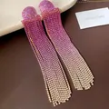 Detailaufnahme von funkelnden Strass-Quastenohrringen mit pinkfarbenem Farbverlauf - Gold Farbverlauf Quaste / Lila Verlauf