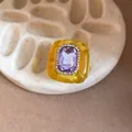Close-up of a vintage resin ring with a large purple gemstone and rhinestone border. - Yellow and Light Purple