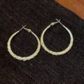 Close-up of golden braided texture hoop earrings with elegant minimalist design. - Twisted Pattern Hoop (HE29538) / Gold