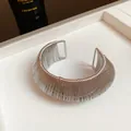 Detailed view of a silver metallic wire-wrapped open cuff bracelet with a bold design. - Silver